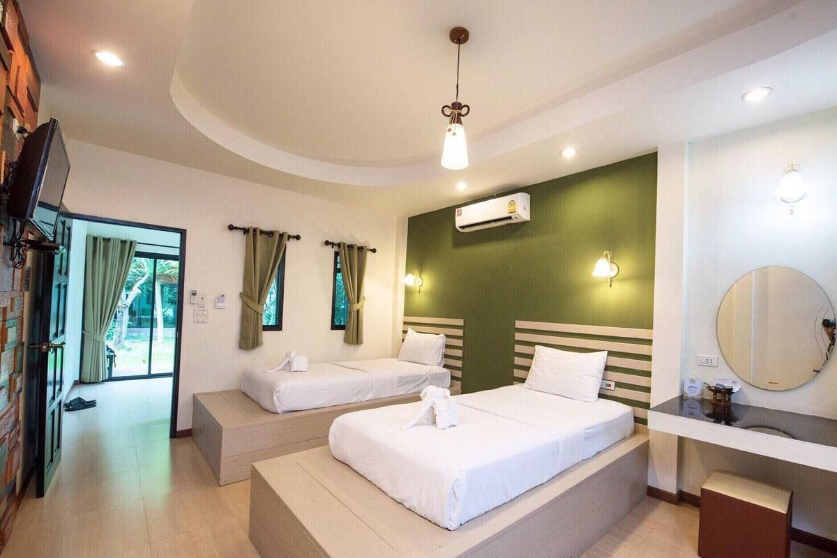 Une chambre d’hôtel avec deux lits, une télévision, la climatisation, un miroir et une vue sur l’extérieur.