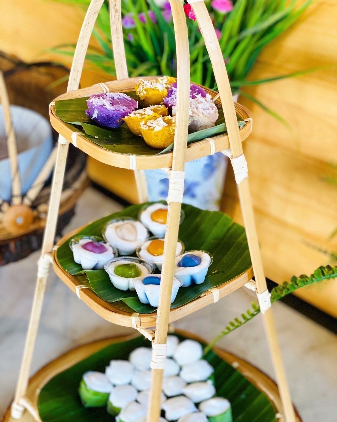 A multi-tiered bamboo stand with various colorful desserts.
