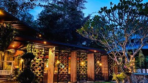 A well-lit garden with a variety of plants and a small table. - Baansuan Leelawadee Resort Nan (Nan)