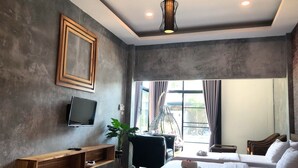 A modern hotel room with a large bed, a TV, a wooden shelf, and a view of the outdoors. - Baansuan Leelawadee Resort Nan (Nan)
