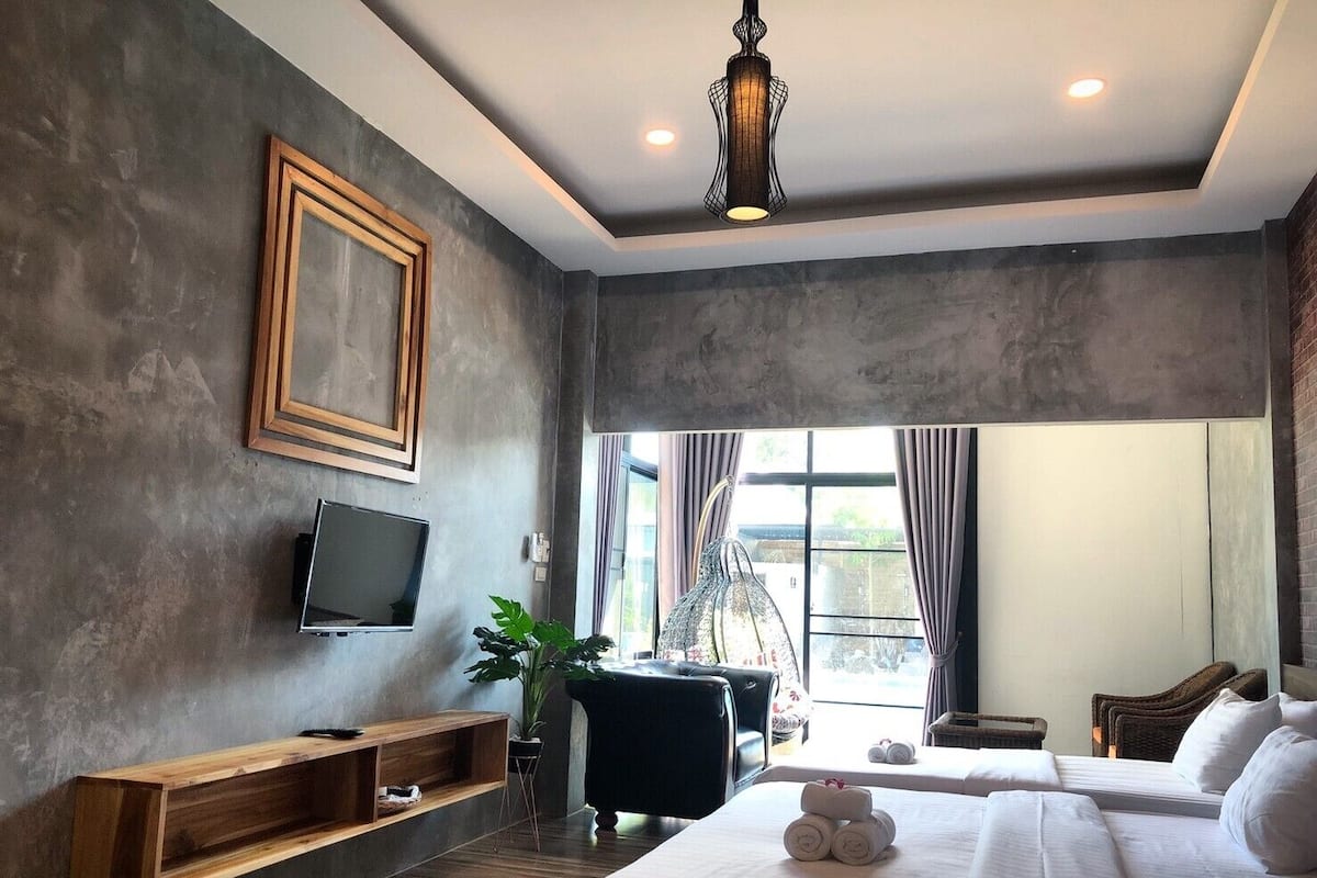 Une chambre d’hôtel moderne avec un grand lit, une télévision, une étagère en bois et une vue sur l’extérieur.