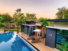 Un hotel moderno con piscina, habitaciones numeradas y zonas de estar al aire libre.
