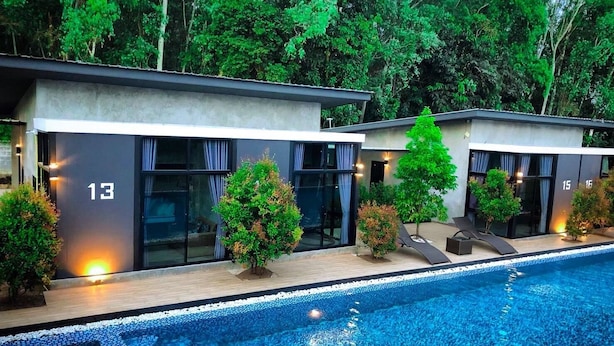 A modern hotel with a swimming pool, numbered rooms, and lush greenery. - Baansuan Leelawadee Resort Nan (Nan)