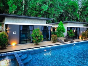A modern hotel with a swimming pool, numbered rooms, and lush greenery. - Baansuan Leelawadee Resort Nan (Nan)