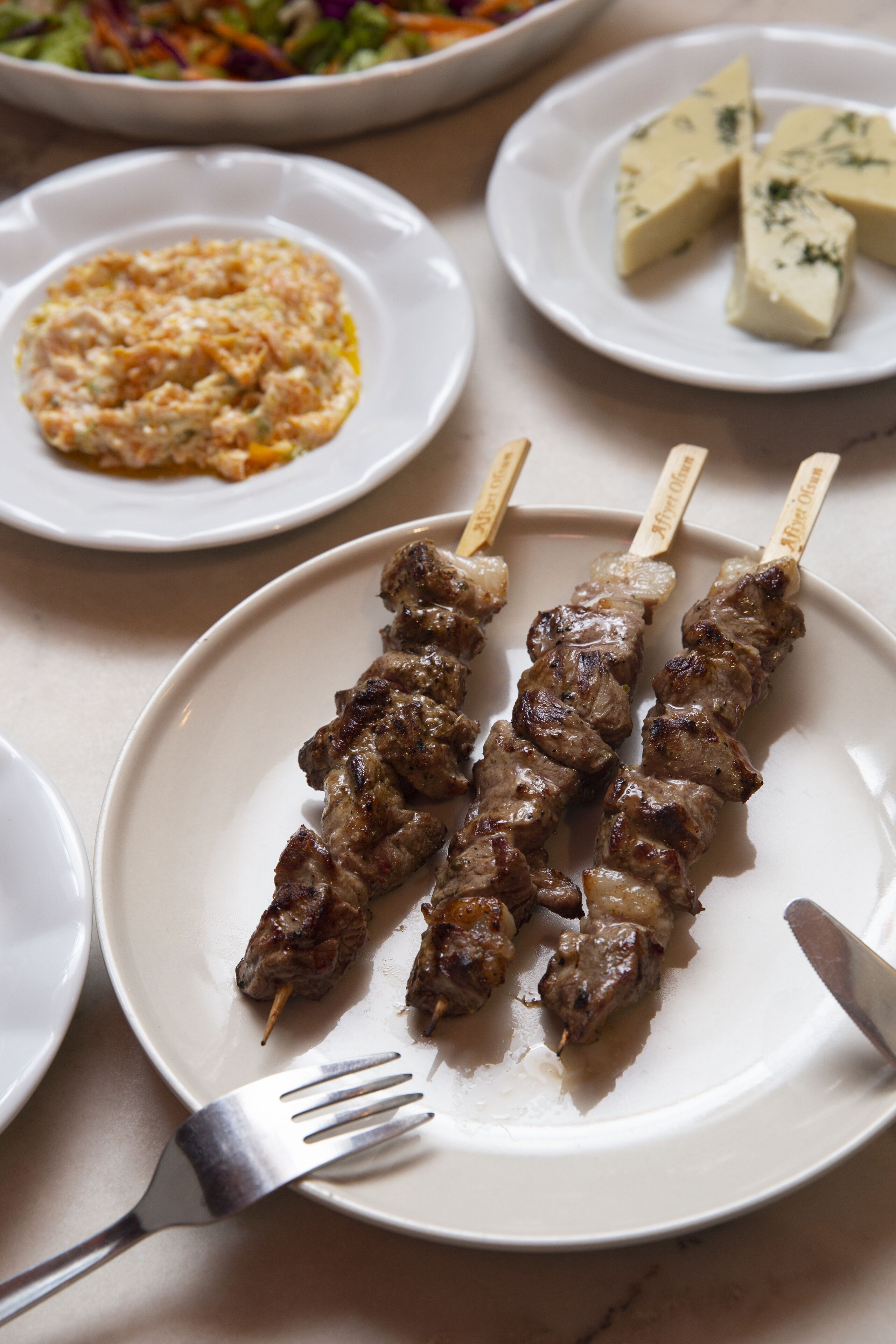 A plate with skewered meat, a fork, and a knife on a table.