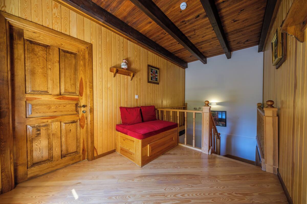Un interior de madera con un banco empotrado, paredes de madera y una escalera.