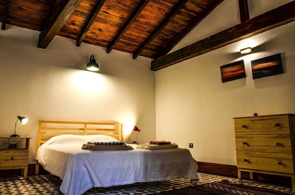 A bedroom with a wooden bed, a nightstand, a dresser, and a checkered floor.