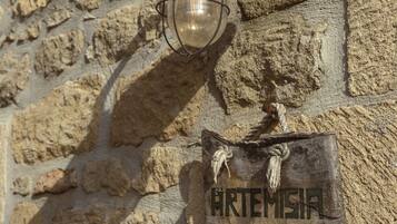 A stone wall with a metal lantern and a wooden sign reading "ARTEMISIA".