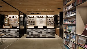 A modern hotel lobby with a central reception desk, bookshelves, and a minimalist design. - LAMP LIGHT BOOKS HOTEL nagoya (Nagoya)
