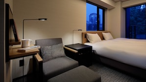 A modern hotel room with a bed, a desk with a lamp, a chair, and a window with a city view. - LAMP LIGHT BOOKS HOTEL nagoya (Nagoya)