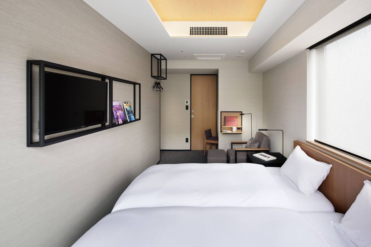 Una habitación de hotel con una cama grande, un escritorio, una silla, un televisor y una ventana.
