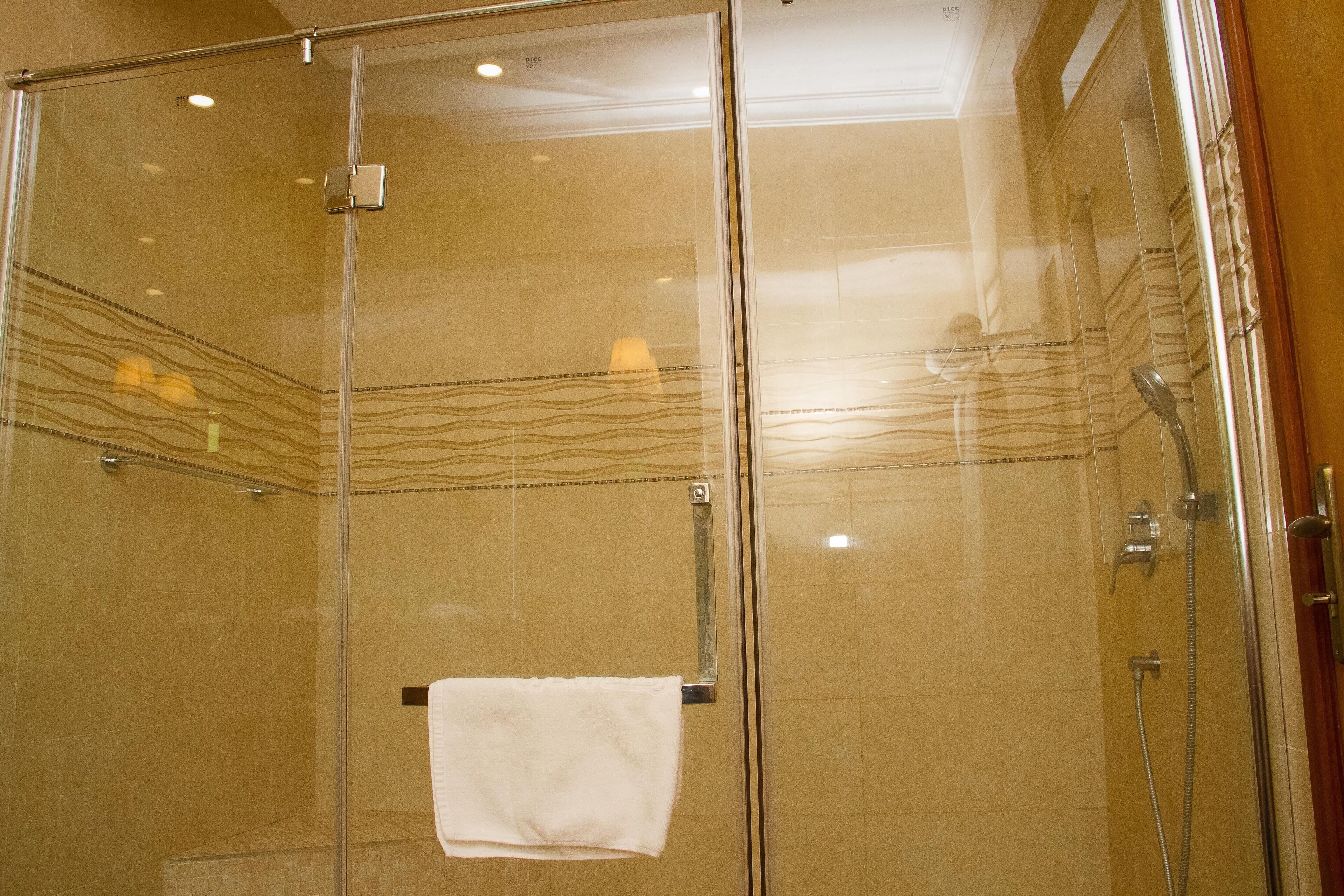 A glass-enclosed shower with a towel hanging on the door handle.