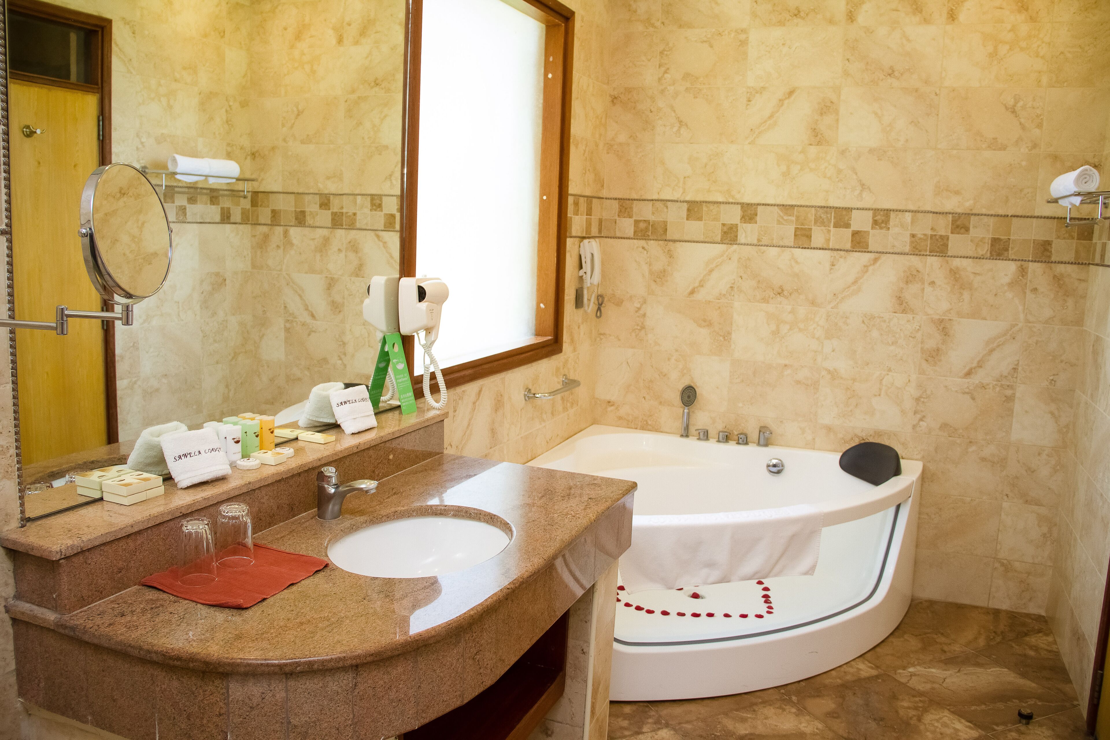 A bathroom with a marble sink, a large mirror, a towel rack, a bathtub, and a window.