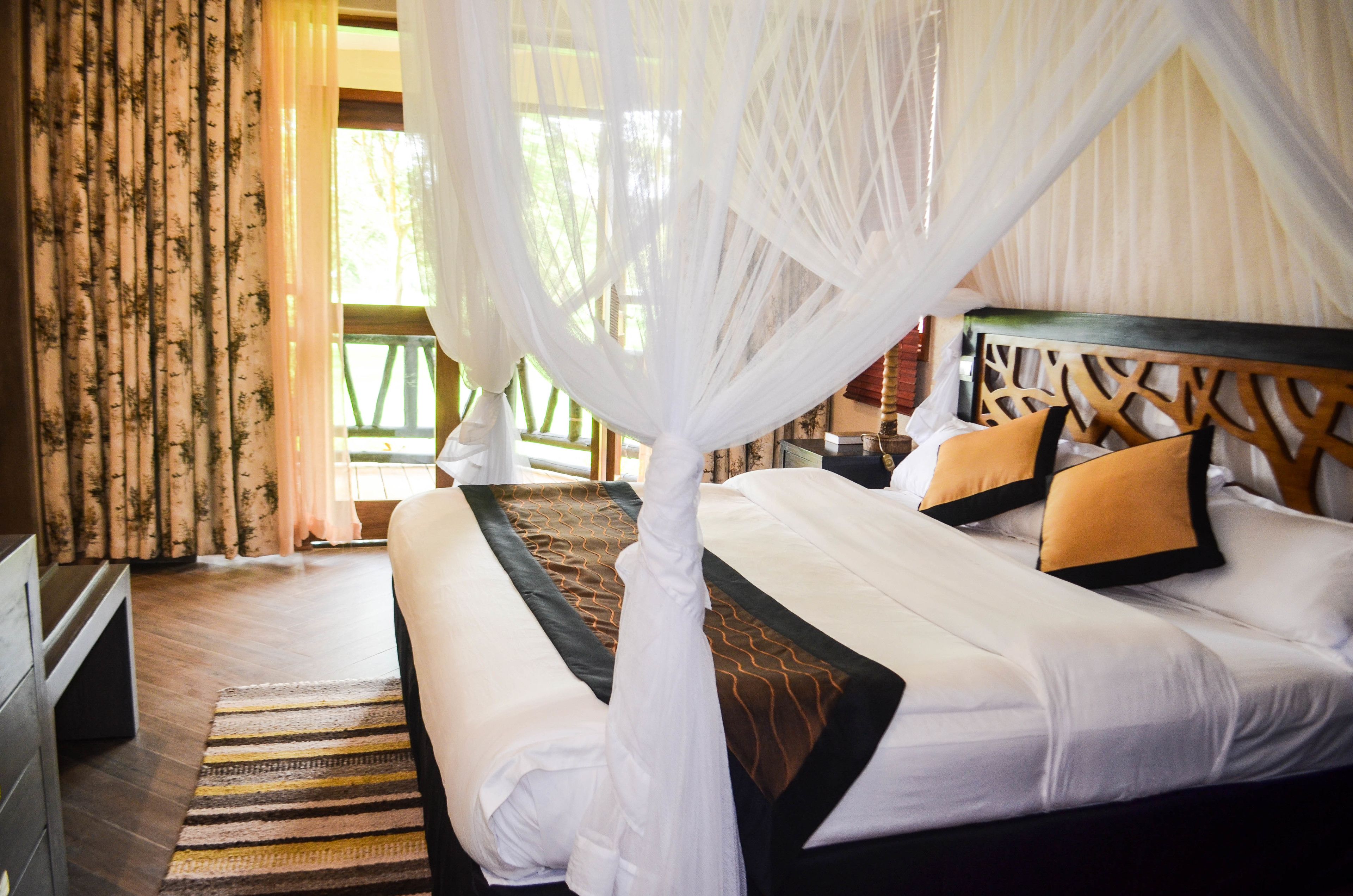 Una habitación de hotel con cama, cortinas, un tapete a rayas y un dosel.