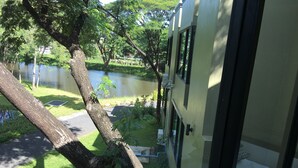 Vista desde el interior de un edificio hacia un estanque rodeado de árboles y un sendero.