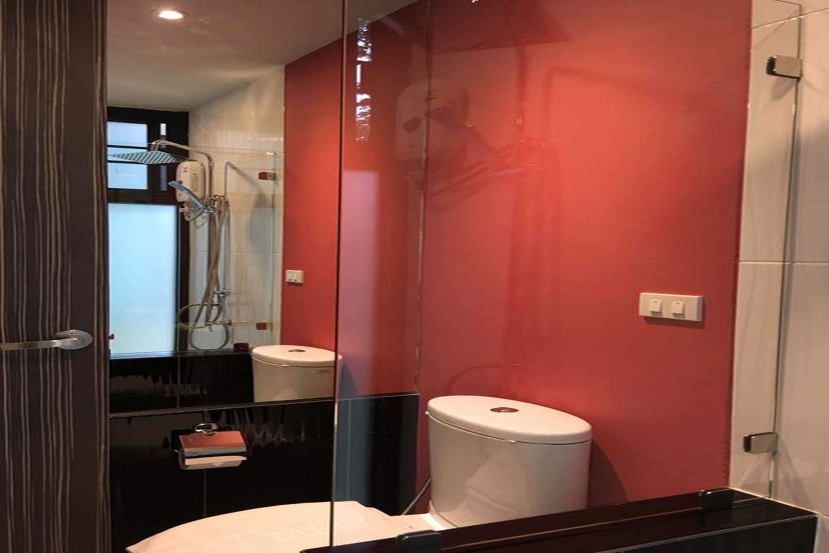 Un baño moderno con cabina de ducha de vidrio, inodoro blanco y tocador negro.