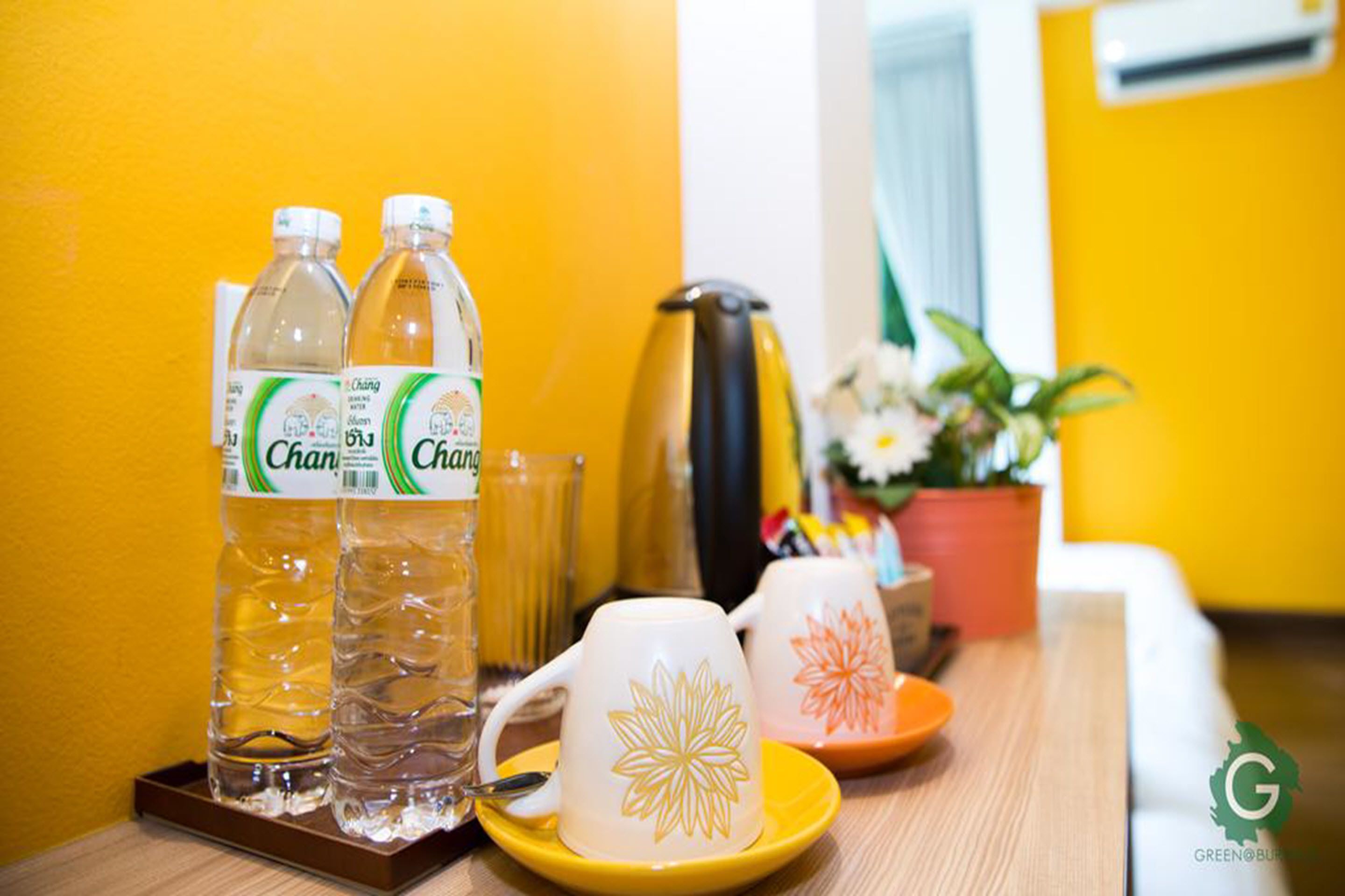 Una mesa con dos botellas de agua Chang, una taza blanca con diseño floral y un plato amarillo.