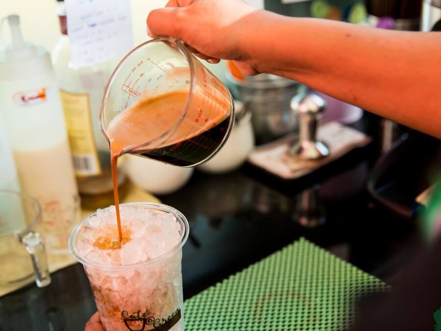 Una persona sirve una bebida en un vaso con hielo.