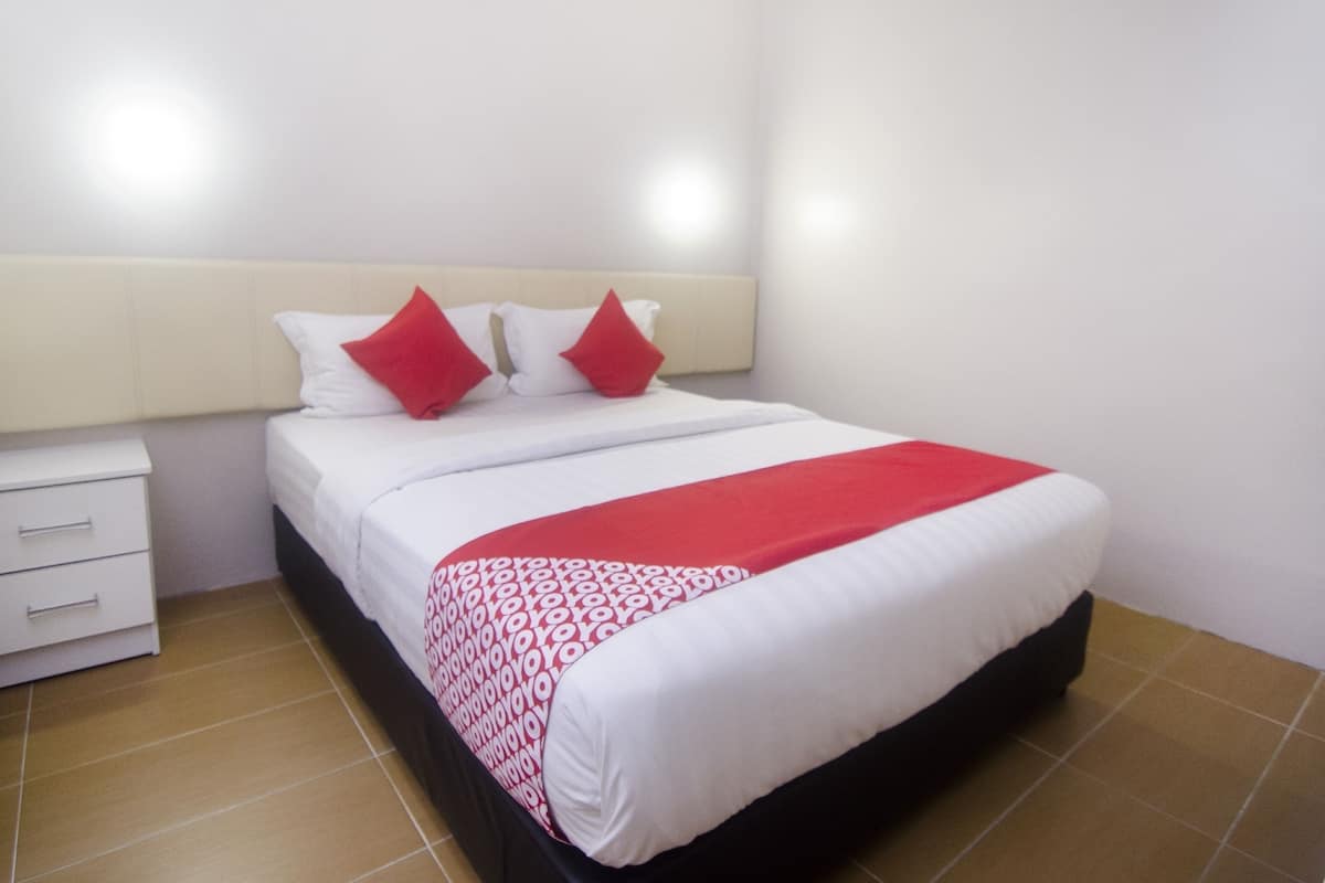 Ein Hotelzimmer mit einem Bett, weißen Wänden und einem Fliesenboden.