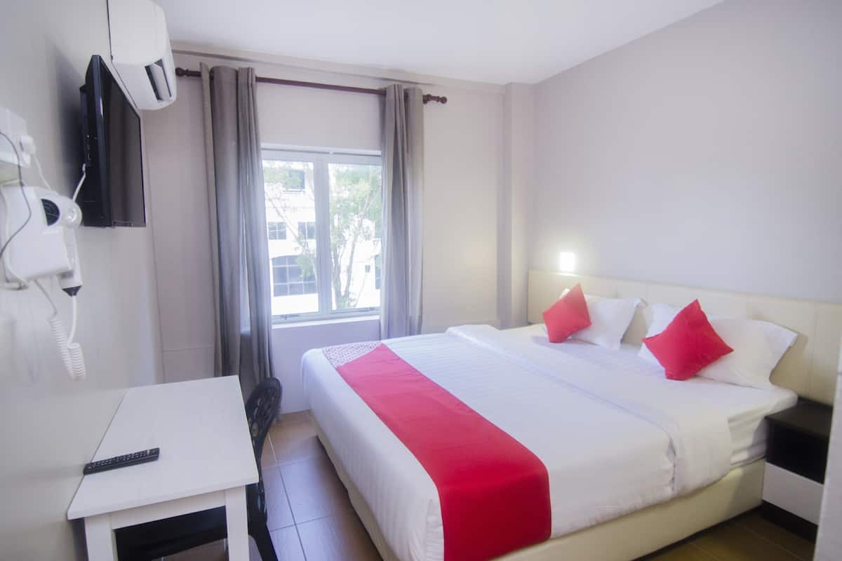 Ein Hotelzimmer mit Bett, Schreibtisch, Föhn und Fenster.