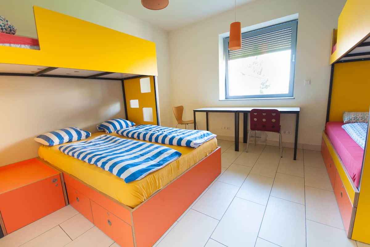 Um quarto com uma cama de solteiro, uma escrivaninha e uma cadeira.