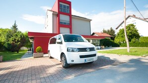 Un coche Volkswagen blanco estacionado frente a un edificio moderno con fachada roja y blanca.