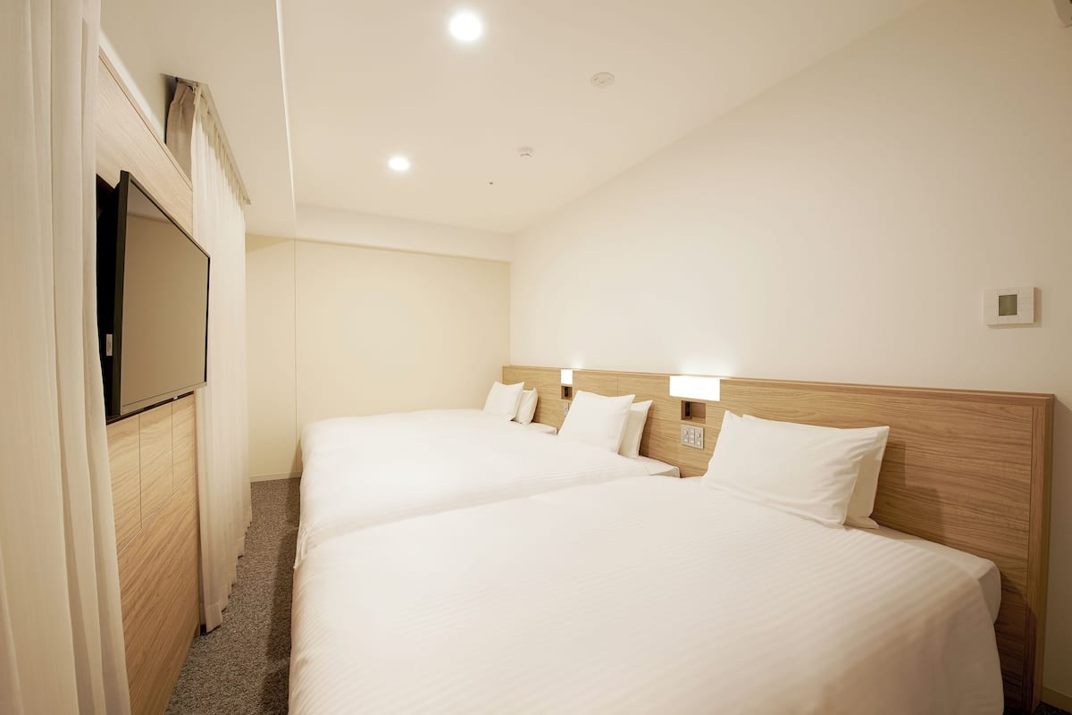 A hotel room with two beds, a TV, and a wooden headboard.