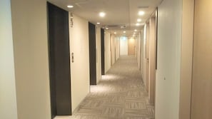 A hotel hallway with carpeted floors and doors on both sides.