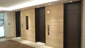 A modern elevator area with wooden paneling and black elevator doors. - Sotetsu Fresa Inn Tokyo Kinshicho (Tokyo)