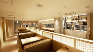 A modern restaurant interior with wooden booths, a bar area, and a kitchen in the background. - Sotetsu Fresa Inn Tokyo Kinshicho (Tokyo)