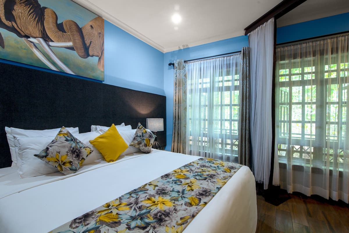 Una habitación de hotel con una cama grande, cubrecama con estampado floral y un cuadro en la pared.