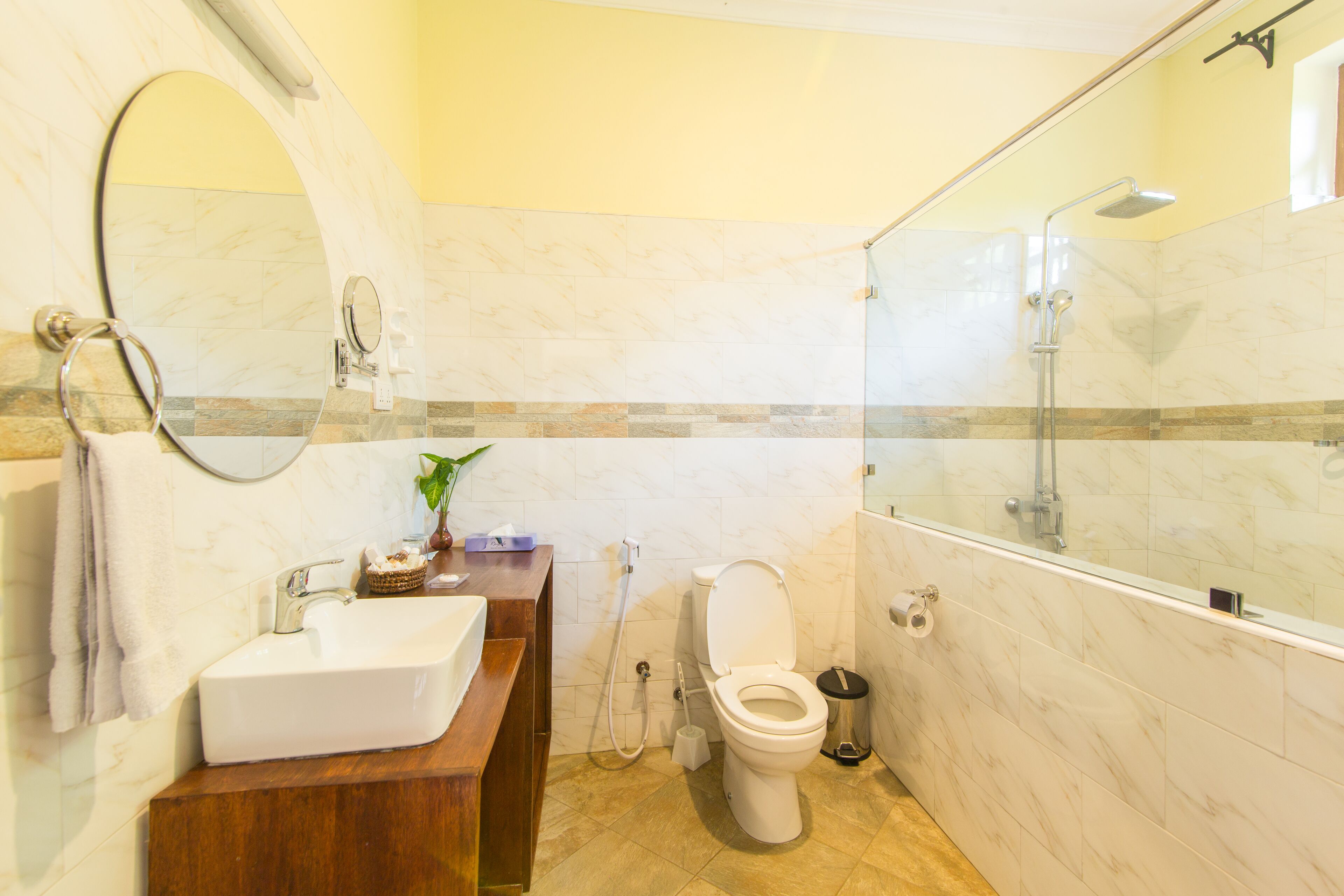 A bathroom with a marble sink, a toilet, and a glass-enclosed shower area.