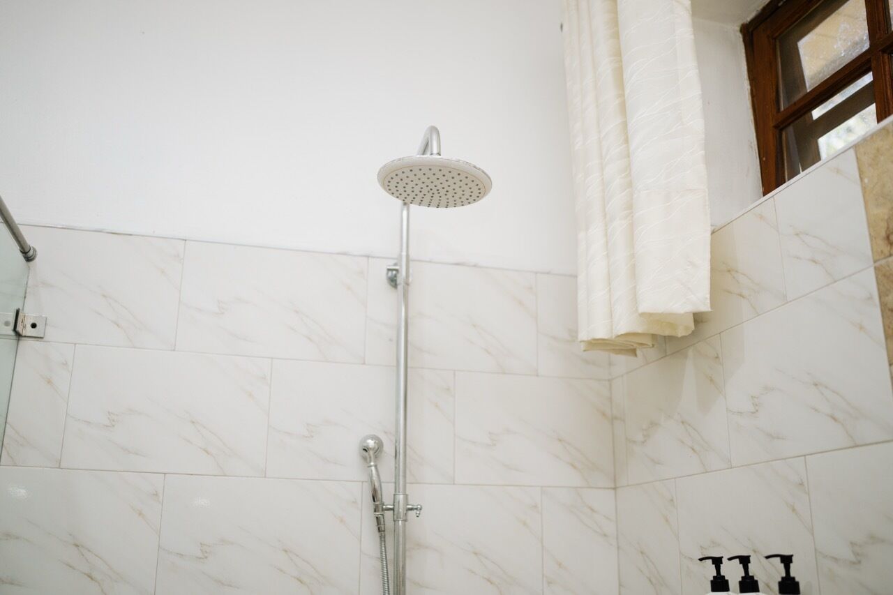 A shower with a handheld showerhead, a wall-mounted control, and a handheld faucet.