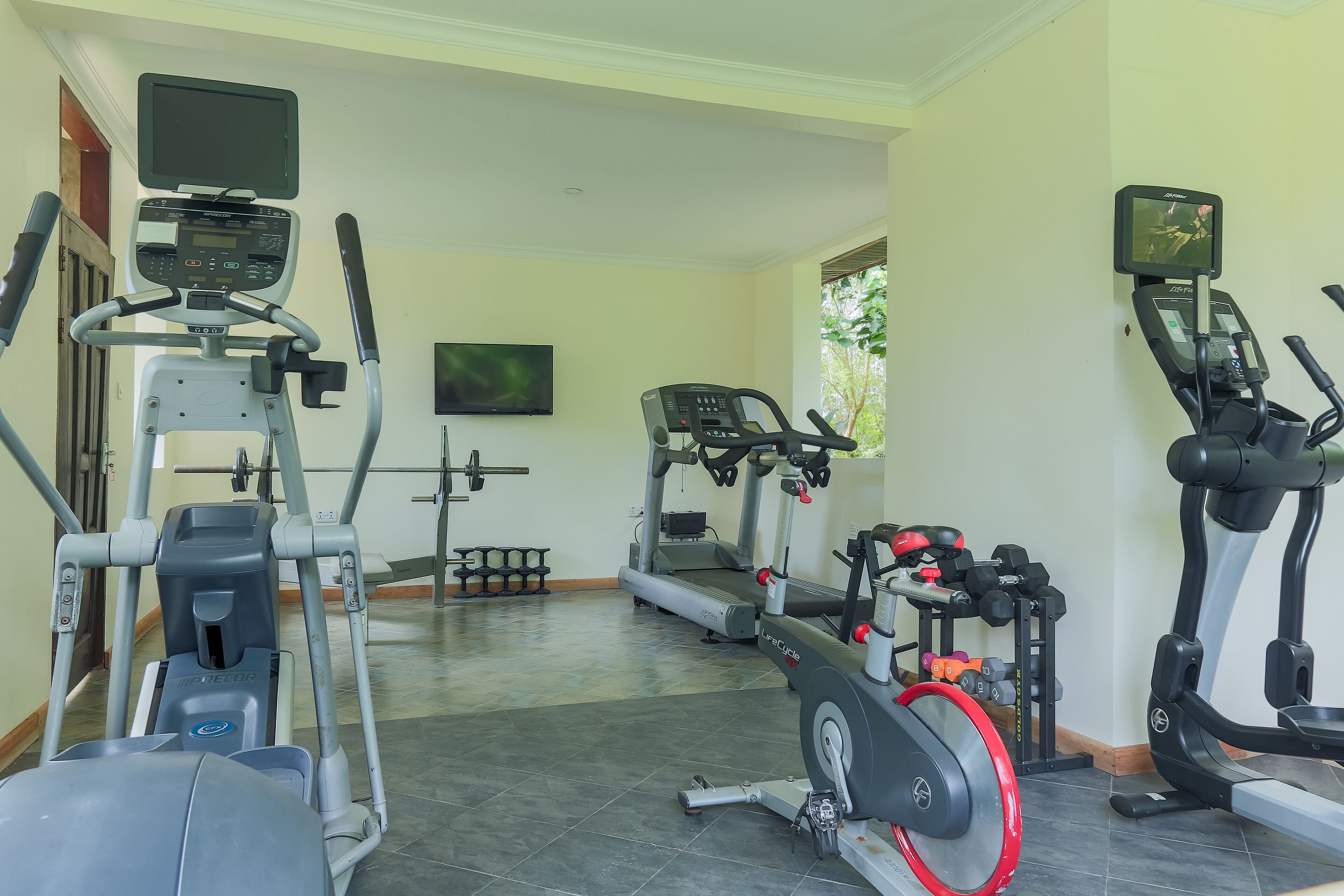 Un gimnasio con varios equipos de ejercicio, incluyendo cintas de correr, elípticas y máquinas de pesas.