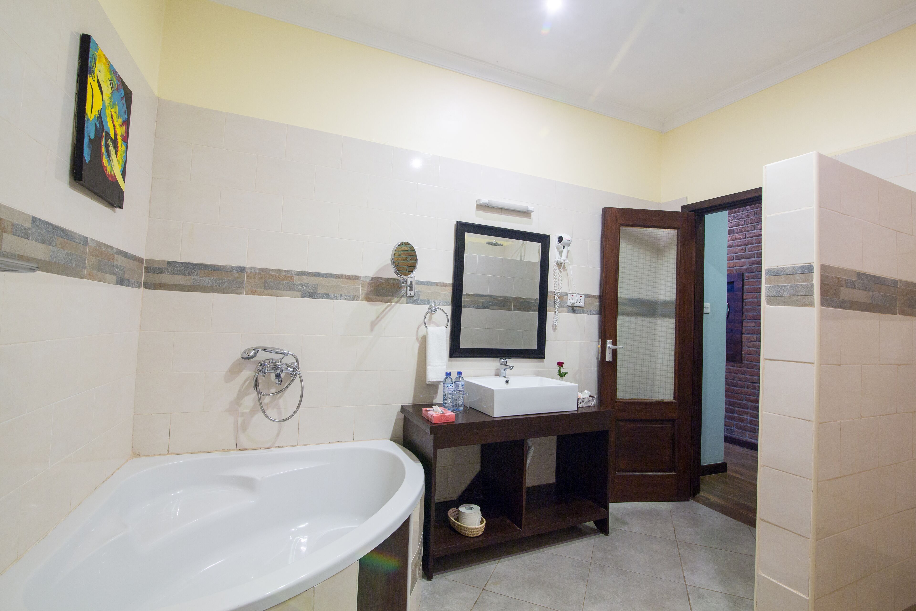 A bathroom with a bathtub, a sink, a mirror, and a door leading to another room.
