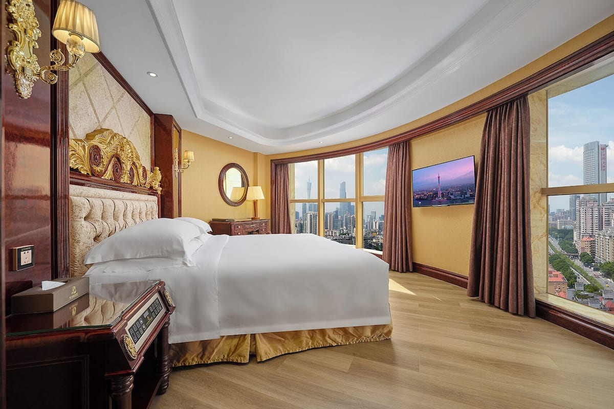 Una habitació d'hotel àmplia amb un llit gran, vistes a la ciutat, televisió i un disseny clàssic.