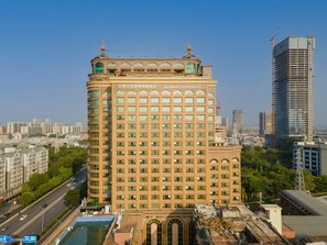 A large, multi-story hotel with a prominent dome and arched windows, surrounded by other buildings and a clear sky. - Yueda Financial City International Hotel (Guangzhou)