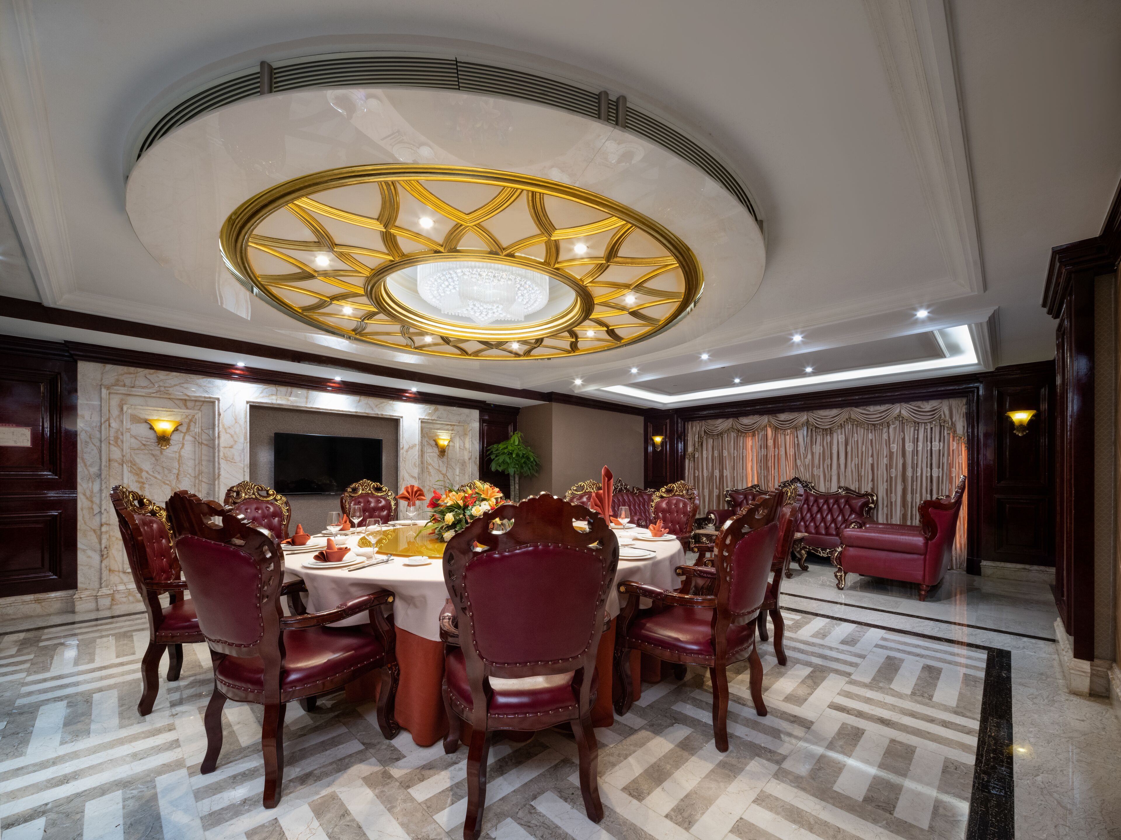 Un comedor elegante con una mesa redonda, sillas tapizadas en rojo y una lámpara decorativa en el techo.