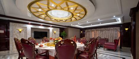 Un comedor elegante con una mesa redonda, sillas tapizadas en rojo y una lámpara decorativa en el techo.