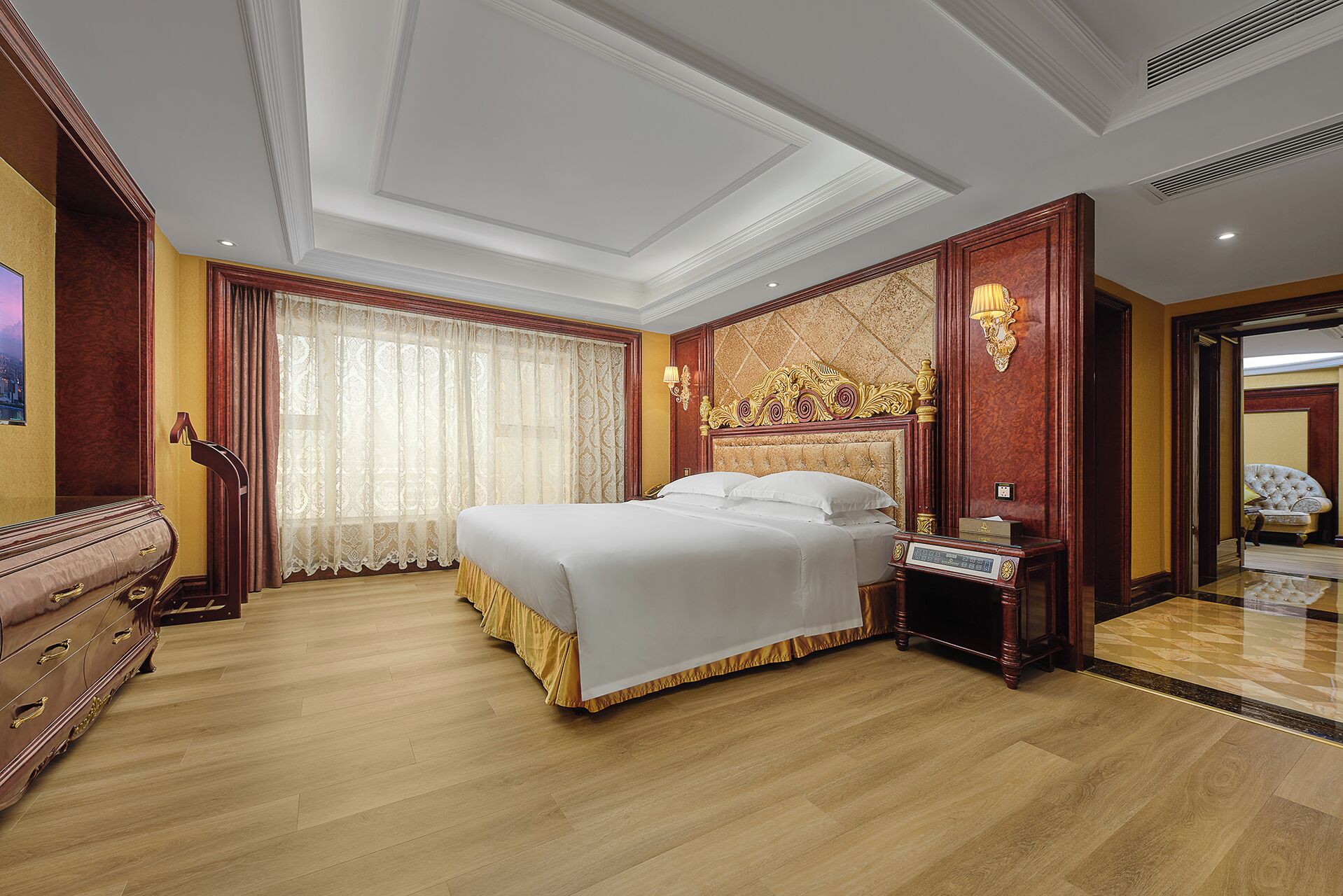 Una habitación de hotel con una cama grande, un aparador de madera, una mesita de noche y un espejo.