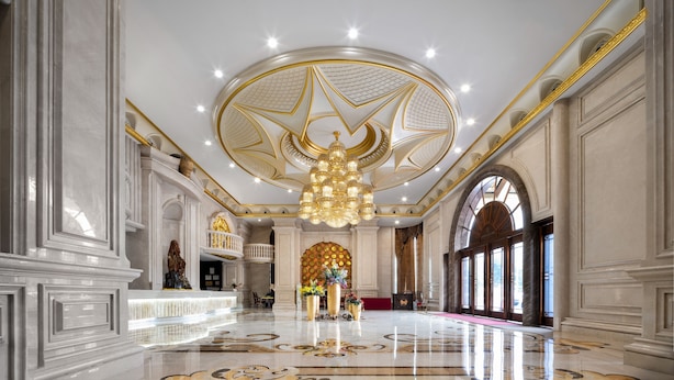 Un lobby imponente con diseño de techo en forma de estrella, suelo de mármol y un candelabro central.