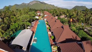 A resort with a long swimming pool, multiple bungalow-style buildings, and lush tropical vegetation. - The Privacy Beach Resort & Spa (Sam Roi Yot)