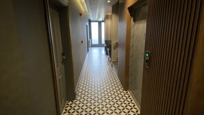 A hallway with patterned flooring, a wooden panel wall, and a door on the left. - Sarikamis Aras Otel (Sarikamis)