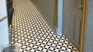 A hallway with patterned flooring, a door with a gold frame, and a wall-mounted light fixture. - Sarikamis Aras Otel (Sarikamis)