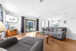 A modern living room with a grey sofa, a wooden coffee table, and a flat-screen TV mounted on the wall. - Carefree Getaways 2 Bedroom Condo by RedAwning (Branson)