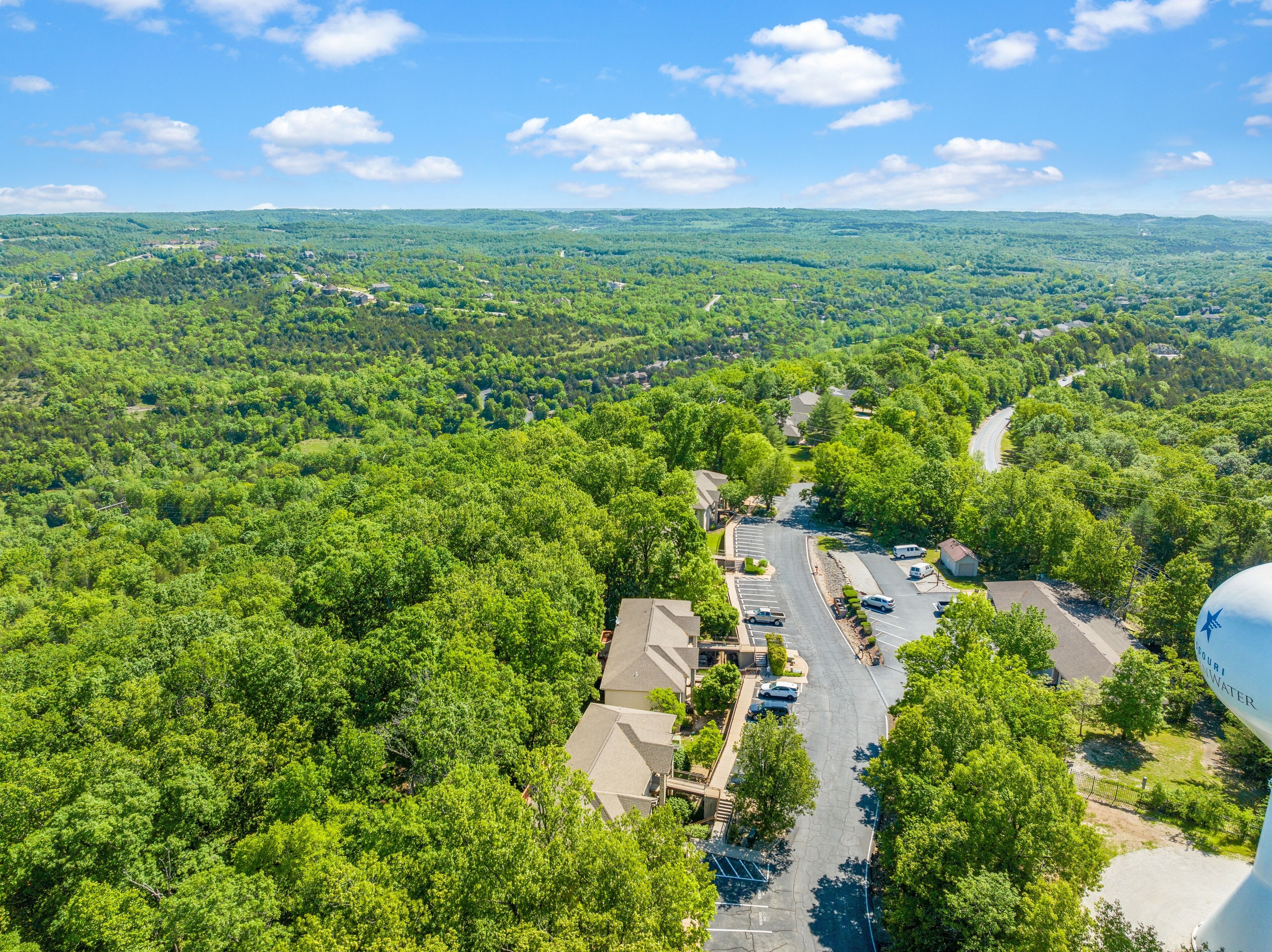 An aerial view of a residential area with houses, roads, and surrounding greenery.