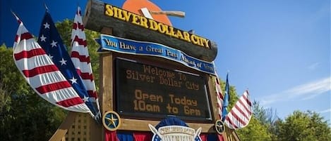 Placa de boas-vindas para Silver Dollar City com mensagem e horário de funcionamento.