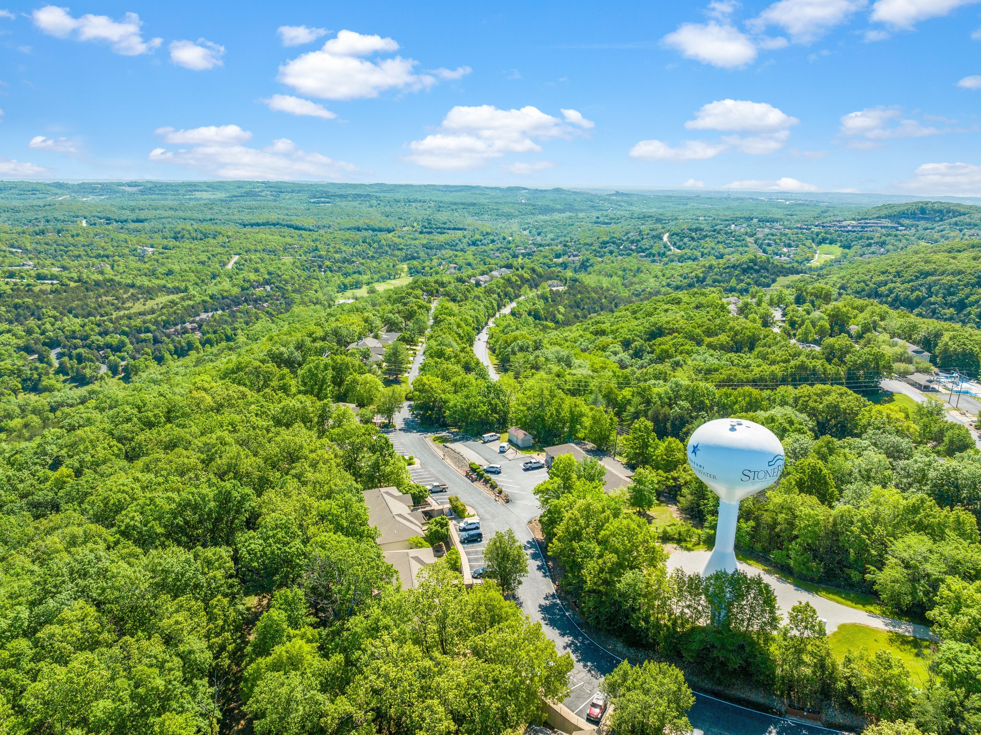 An aerial view of a residential area with a prominent water tower, roads, and greenery.