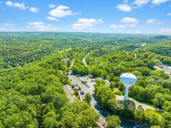 An aerial view of a residential area with a prominent water tower, roads, and greenery.