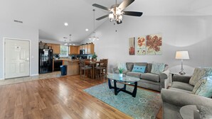 A spacious living area with a wooden floor, a grey sofa set, a coffee table, and a ceiling fan. - Heavenly Hideaway 2 Bedroom Condo by RedAwning (Branson West)